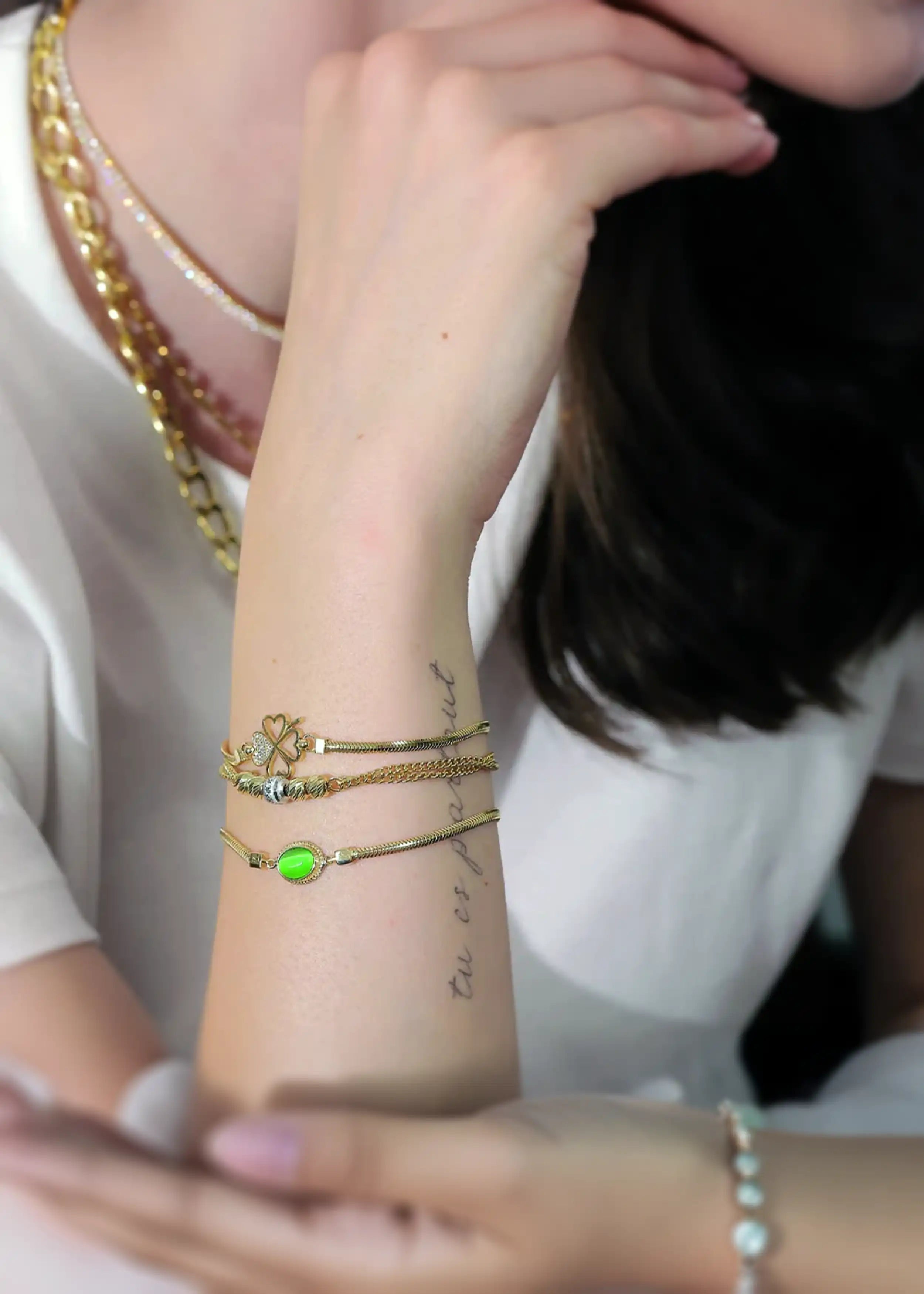 Die goldene Armbänder mit einem Kleeblatt-Anhänger aus vier Herzchen mit funkelnden Steinen