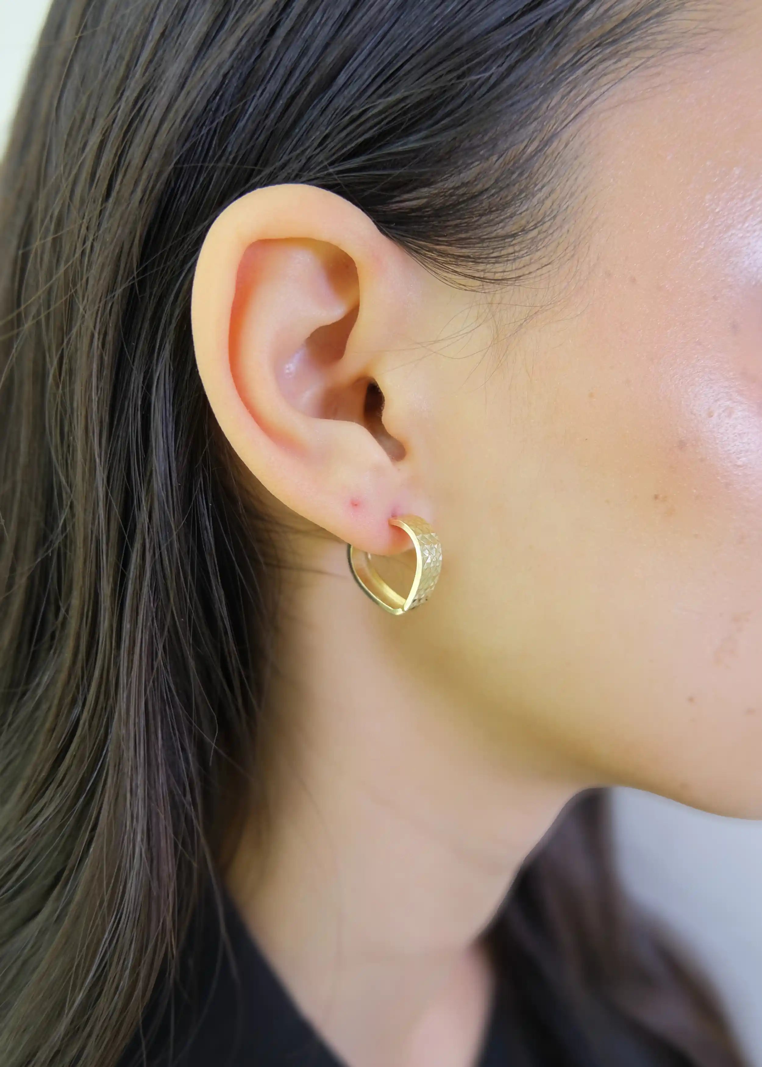 Eine Damme trägt Creolen Gold-Ohrringe in Herzform mit Muster aus 14 Karat Gelbgold mit Schnappverschluss – Minimalistisch, romantisch und klassisch