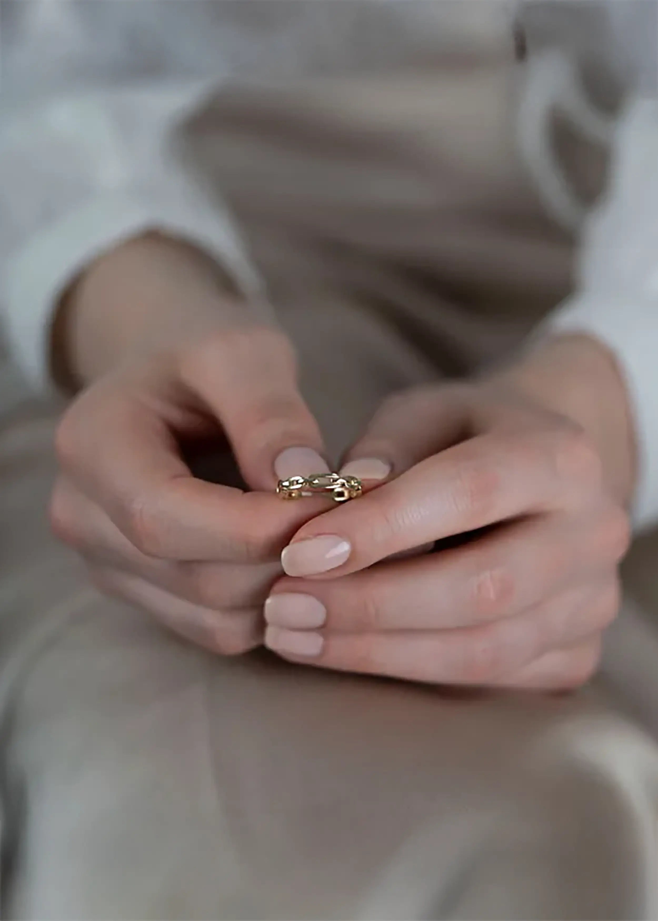 Flexibler 14K Goldring im Ankerketten-Design am Finger einer Person mit naturfarbenen Nägeln und weißem Oberteil – minimalistischer Schmuck aus Gelb-, Weiß- oder Roségold, am Finger einer Person. Die Person trägt ein weißes Kleidungsstück und hat naturfarbene Nägel.